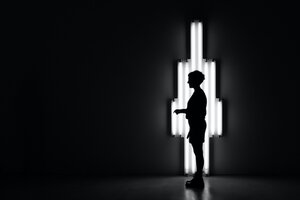 Person vor hellen Neonröhren und schwarzem Hintergrund
