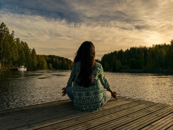 Frau meditiert am See